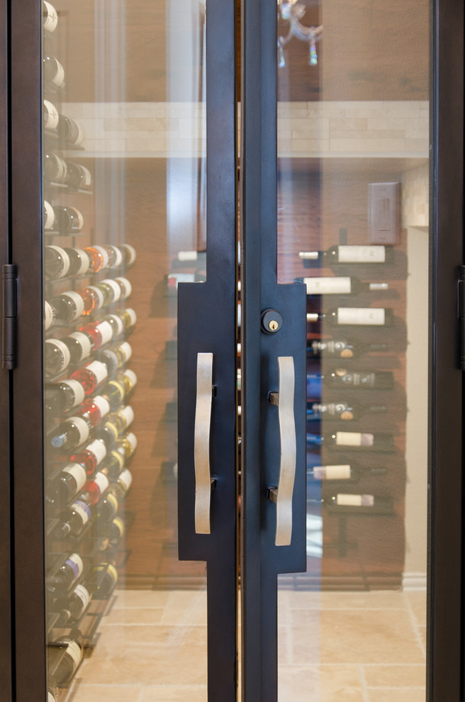 This is an example of a mediterranean wine cellar in Dallas with travertine flooring and display racks.