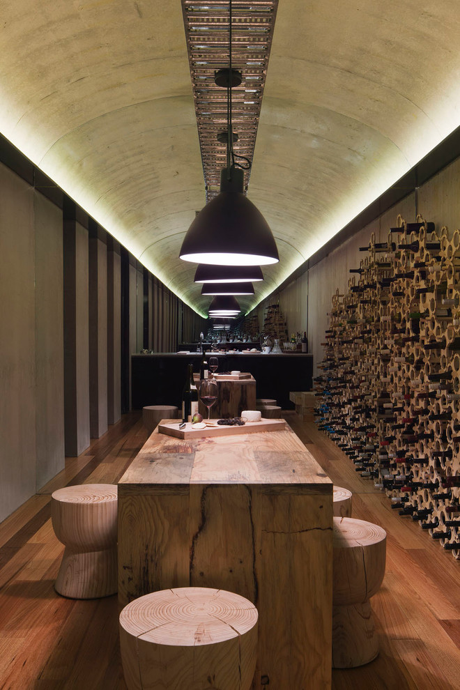 Cette image montre une cave à vin design avec un sol en bois brun, des casiers et un sol marron.
