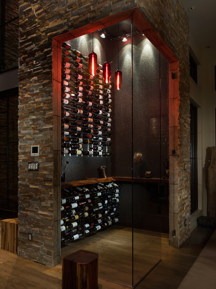 Idée de décoration pour une grande cave à vin design avec parquet clair et des casiers.
