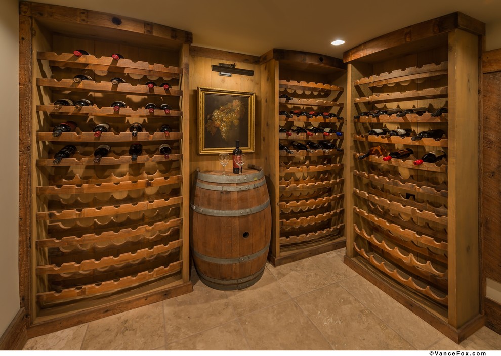 Small rustic wine cellar in Other with travertine flooring and storage racks.