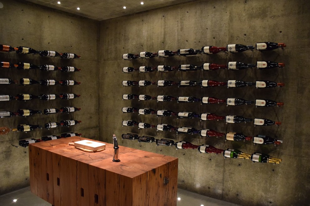 Idées déco pour une cave à vin contemporaine de taille moyenne avec sol en béton ciré et un présentoir.