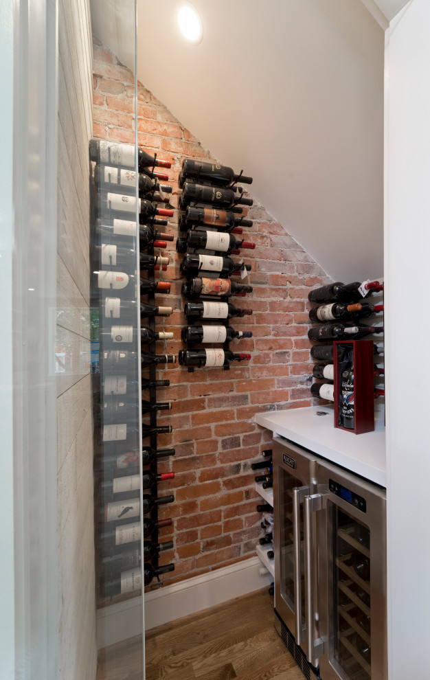 Photo of a small modern wine cellar in DC Metro with medium hardwood flooring and display racks.