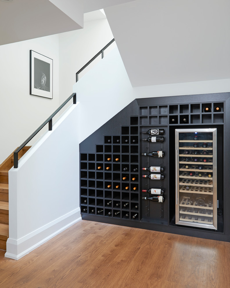 Idée de décoration pour une cave à vin design avec un sol en bois brun et des casiers.