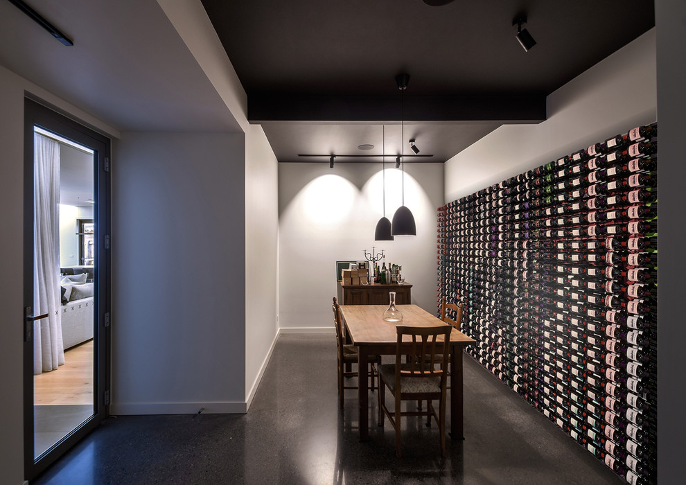Medium sized modern wine cellar in Melbourne with concrete flooring, grey floors and storage racks.