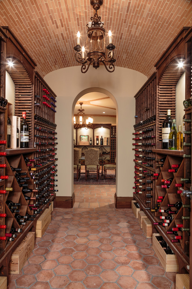 Bild på en mycket stor medelhavsstil vinkällare, med klinkergolv i terrakotta, vinhyllor och rött golv