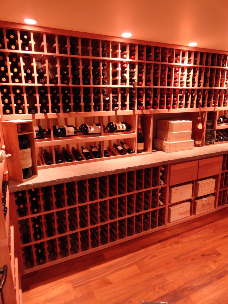 Large romantic wine cellar in Los Angeles with light hardwood flooring, storage racks and orange floors.
