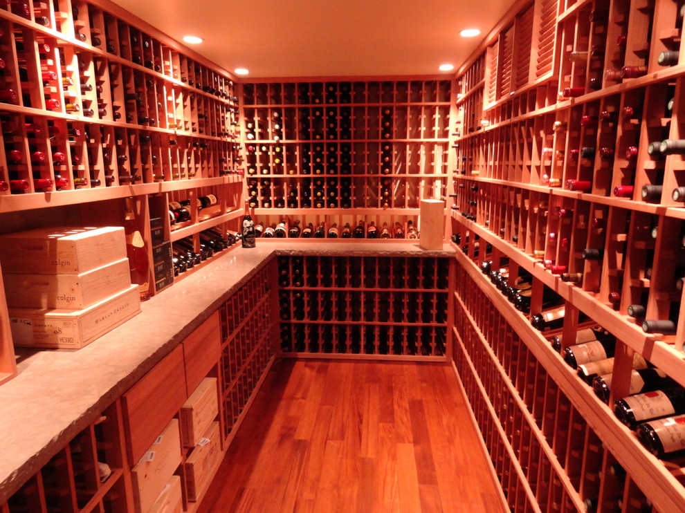 Cette image montre une grande cave à vin traditionnelle avec parquet clair, des casiers et un sol orange.