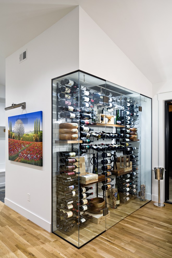Contemporary wine cellar in Denver with light hardwood flooring and storage racks.