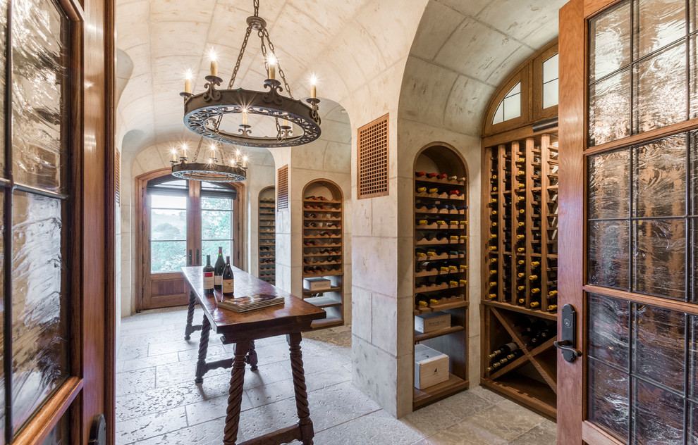 Large mediterranean wine cellar in San Francisco with storage racks, travertine flooring and grey floors.