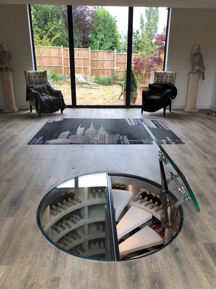 This is an example of a medium sized modern wine cellar in Cambridgeshire with limestone flooring, storage racks and white floors.