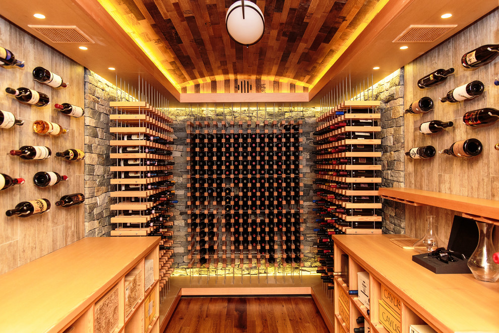 Cette photo montre une cave à vin chic avec un sol en bois brun et des casiers.