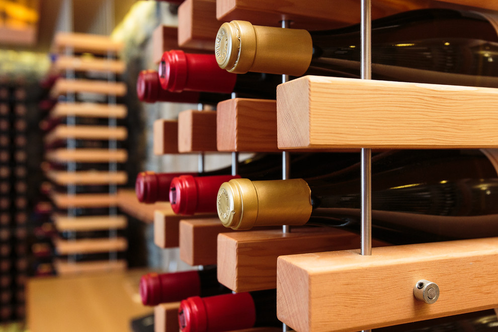 Aménagement d'une cave à vin contemporaine de taille moyenne avec des casiers et parquet clair.