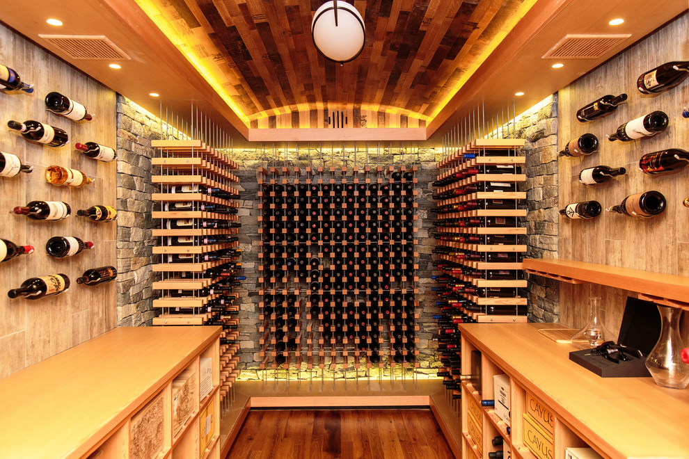 Réalisation d'une cave à vin design de taille moyenne avec des casiers et parquet clair.