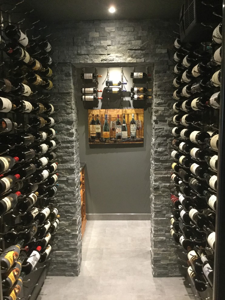 Cette photo montre une cave à vin tendance de taille moyenne avec un sol en carrelage de porcelaine, un présentoir et un sol gris.