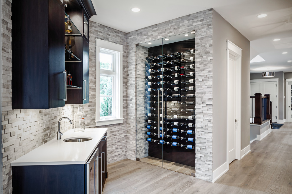 Medium sized classic wine cellar in Grand Rapids with light hardwood flooring and display racks.
