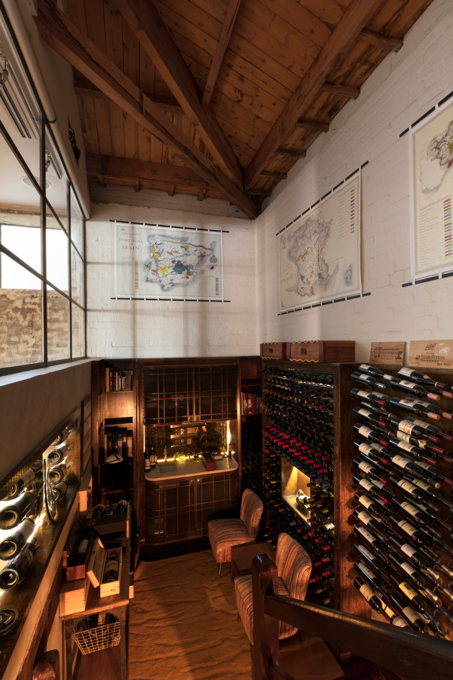 This is an example of an expansive urban wine cellar in Melbourne with dark hardwood flooring and display racks.