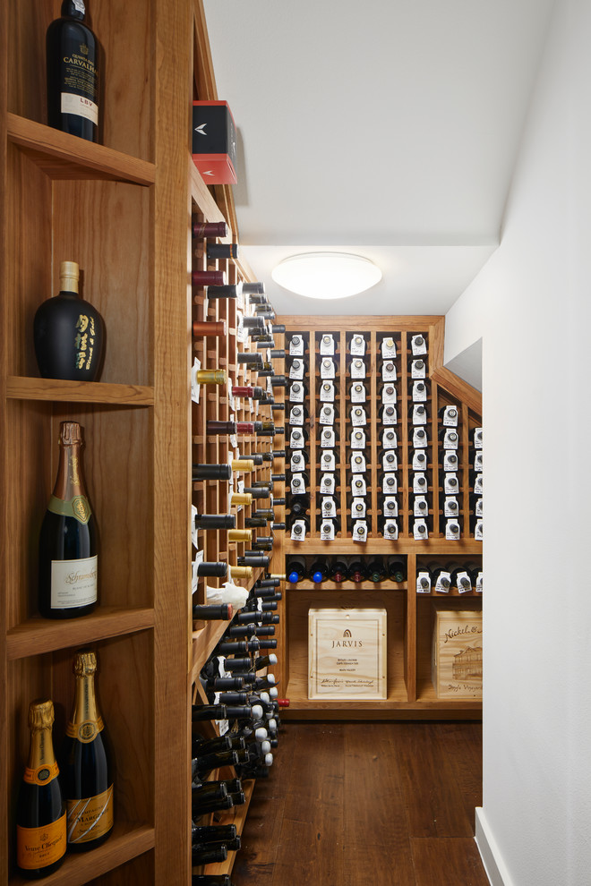 Cette photo montre une cave à vin tendance de taille moyenne avec parquet foncé, des casiers et un sol marron.