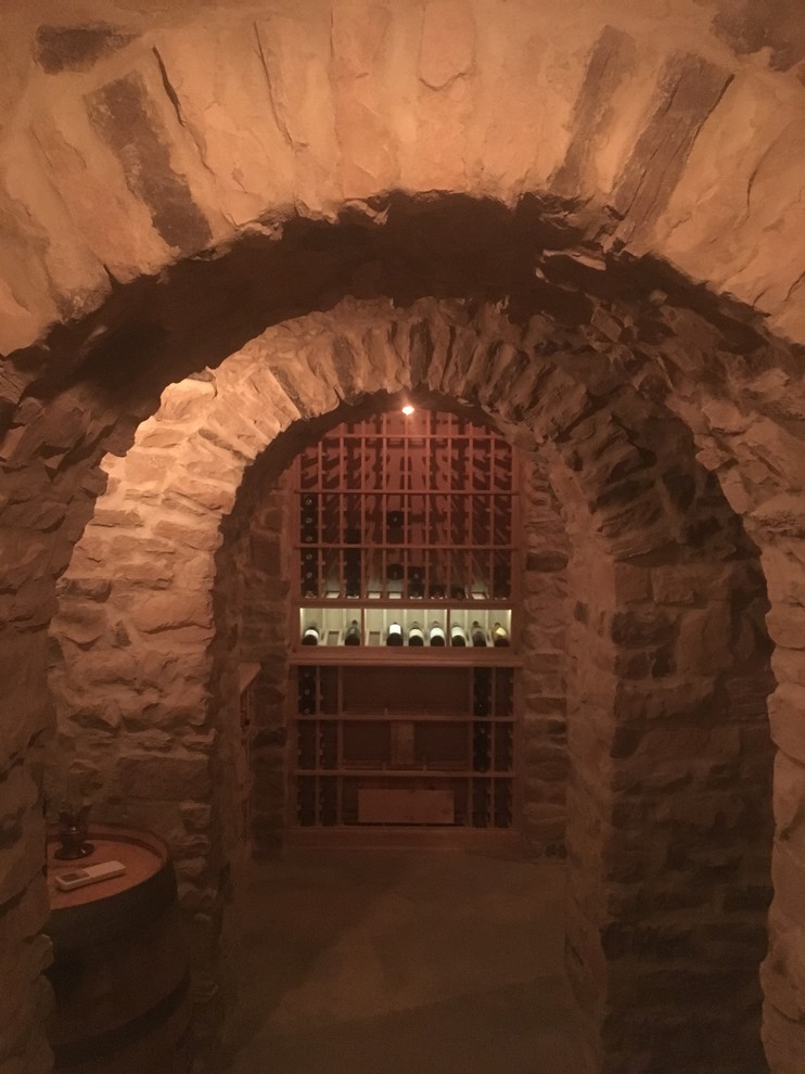Aménagement d'une grande cave à vin classique avec sol en béton ciré, des casiers et un sol gris.