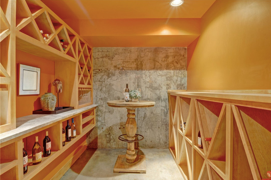 Réalisation d'une petite cave à vin craftsman avec sol en béton ciré et des casiers losange.