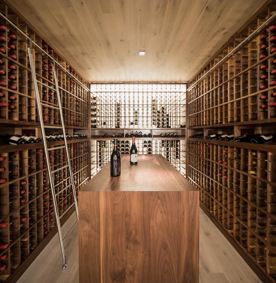 Example of a large trendy medium tone wood floor wine cellar design in Portland Maine with storage racks