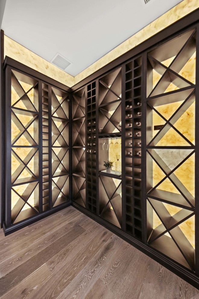 Réalisation d'une très grande cave à vin design avec parquet clair, des casiers losange et un sol gris.