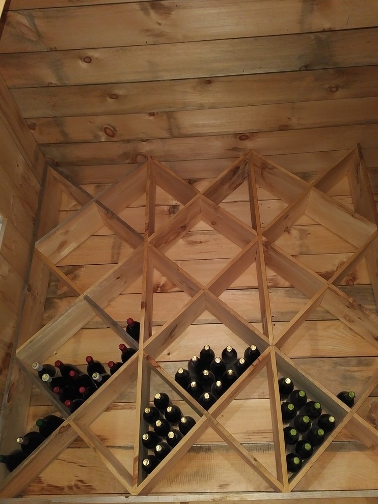 This is an example of a medium sized rustic wine cellar in Ottawa with concrete flooring and display racks.