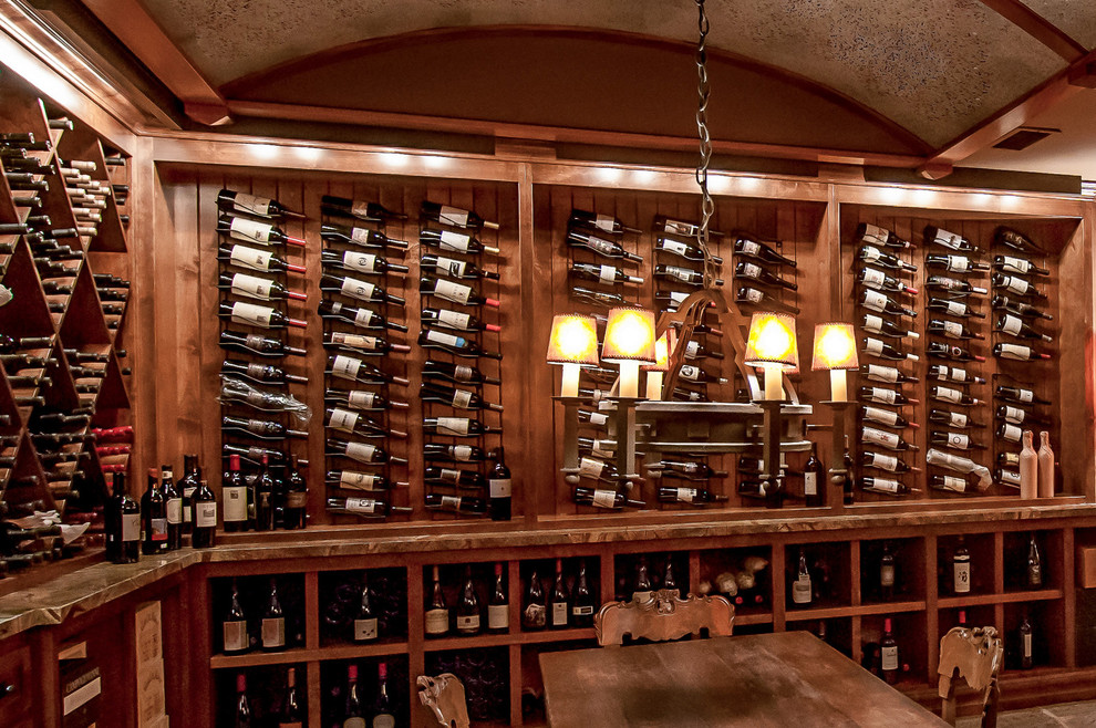 Foto på en stor amerikansk vinkällare, med vinställ med diagonal vinförvaring, skiffergolv och grått golv