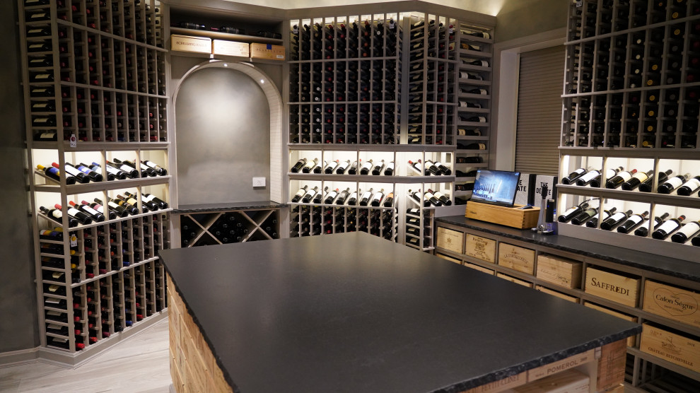 Huge trendy light wood floor and gray floor wine cellar photo in New York with storage racks