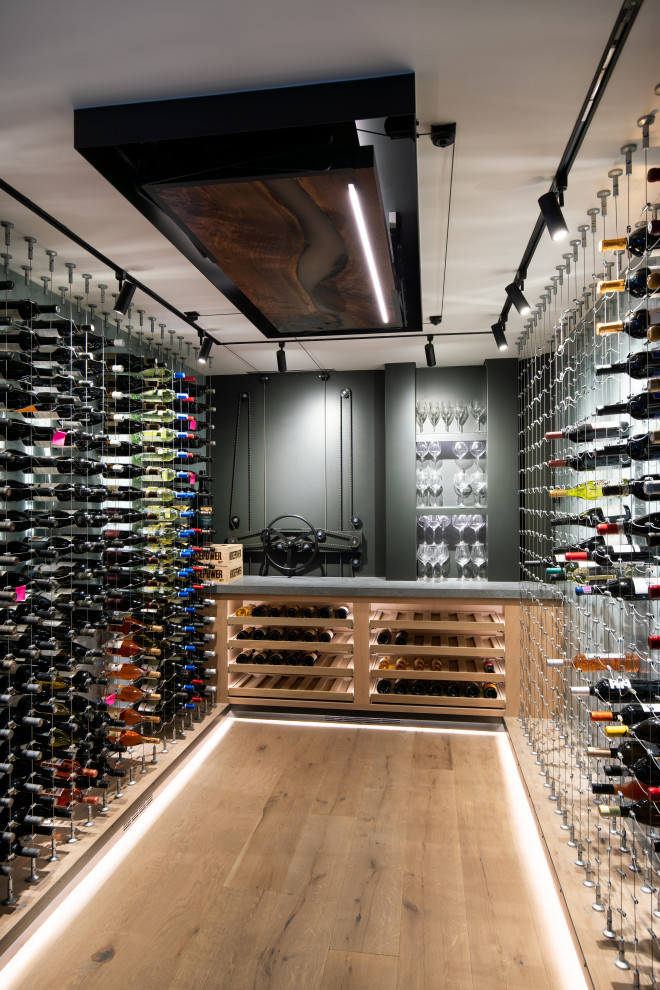 Contemporary wine cellar in Other with light hardwood flooring, storage racks and beige floors.