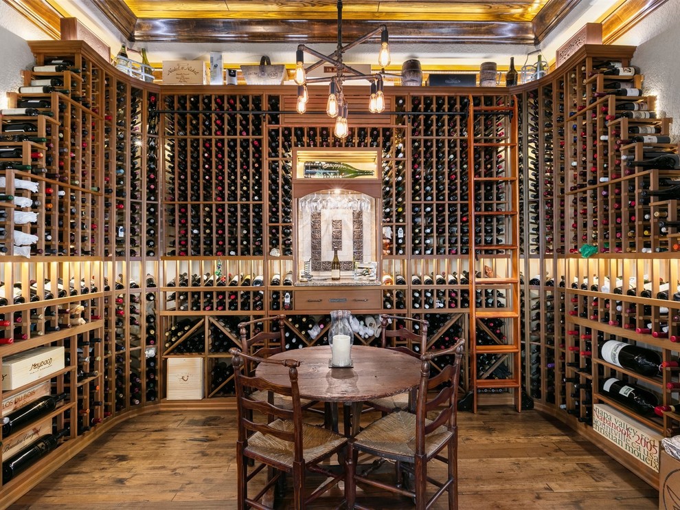 Exemple d'une cave à vin méditerranéenne avec parquet foncé, des casiers et un sol marron.