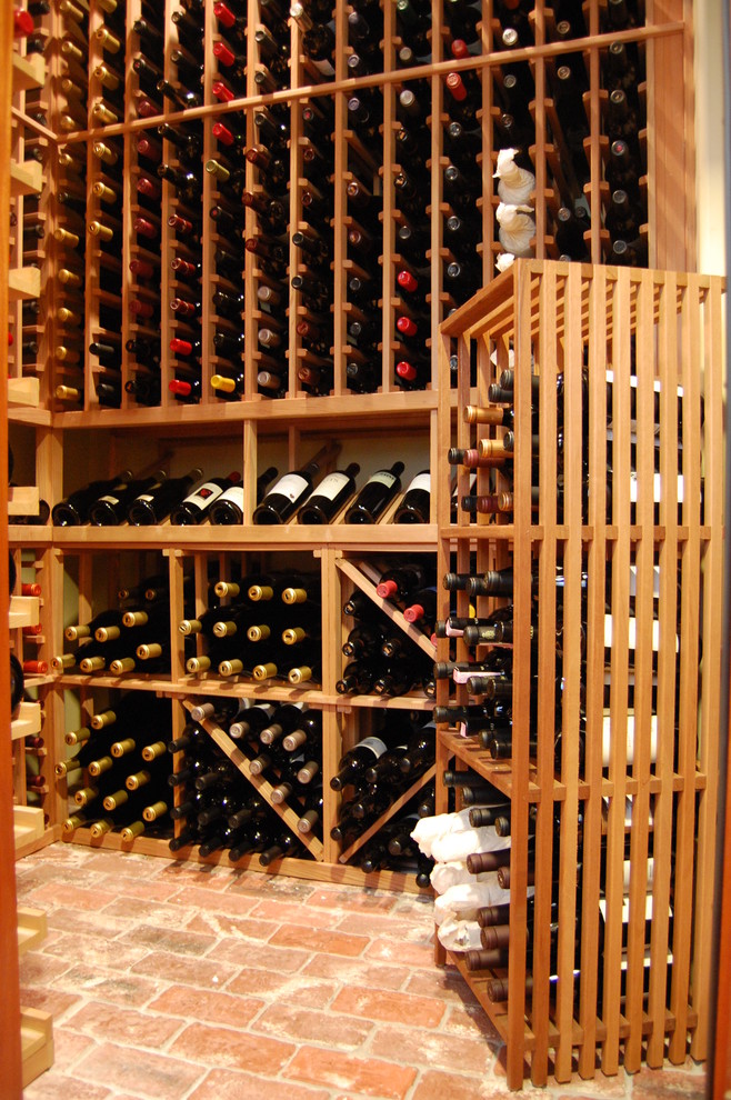 Foto på en stor vintage vinkällare, med tegelgolv, vinhyllor och rött golv