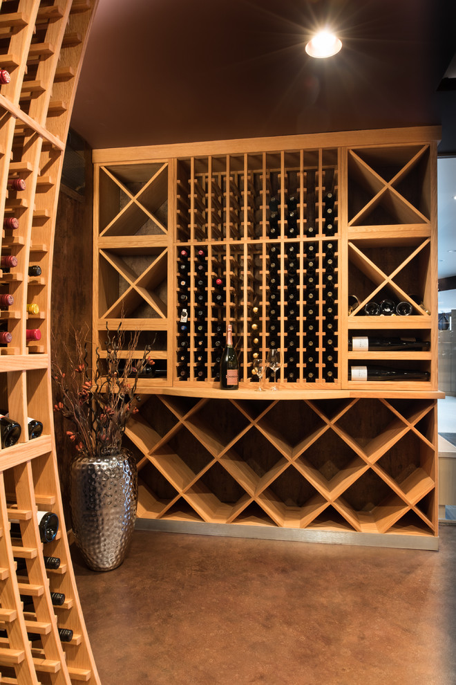 Cette photo montre une grande cave à vin chic avec sol en béton ciré et des casiers losange.