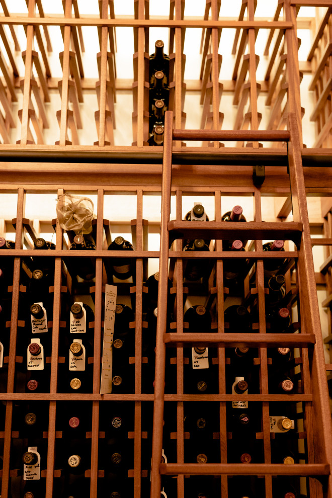 Cette photo montre une cave à vin chic de taille moyenne avec un sol en bois brun, des casiers et un sol marron.