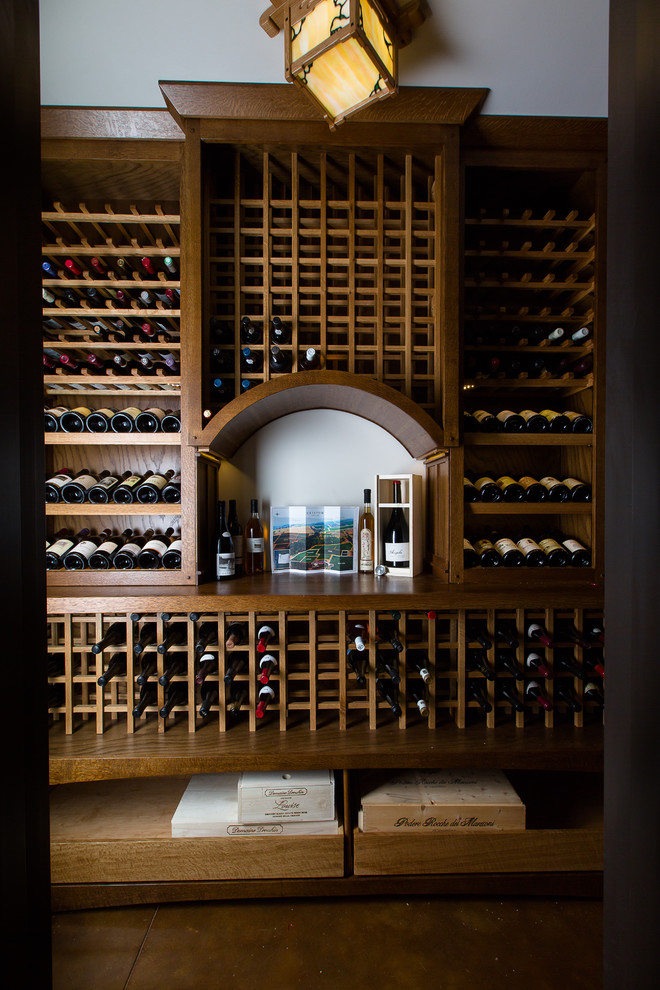 Cette photo montre une petite cave à vin craftsman avec des casiers et sol en béton ciré.