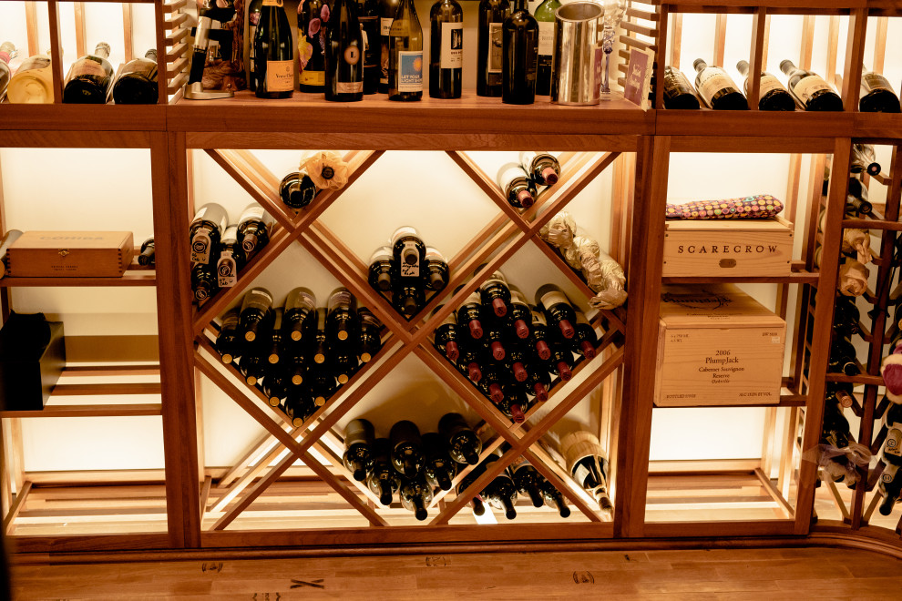 Réalisation d'une cave à vin tradition de taille moyenne avec un sol en bois brun, des casiers et un sol marron.