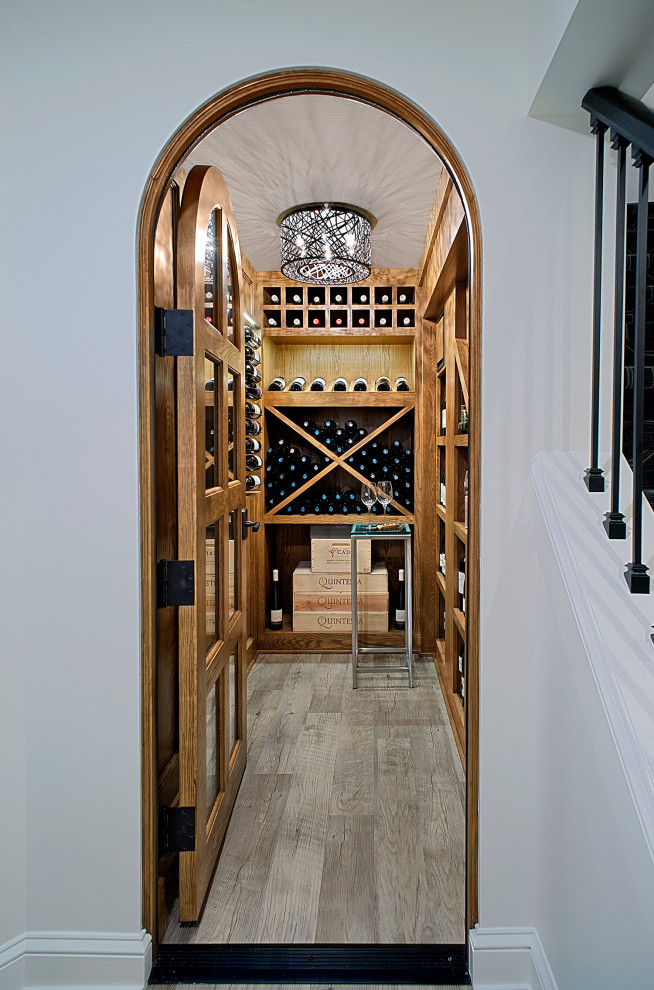 Cette image montre une grande cave à vin craftsman avec parquet clair, un présentoir et un sol gris.