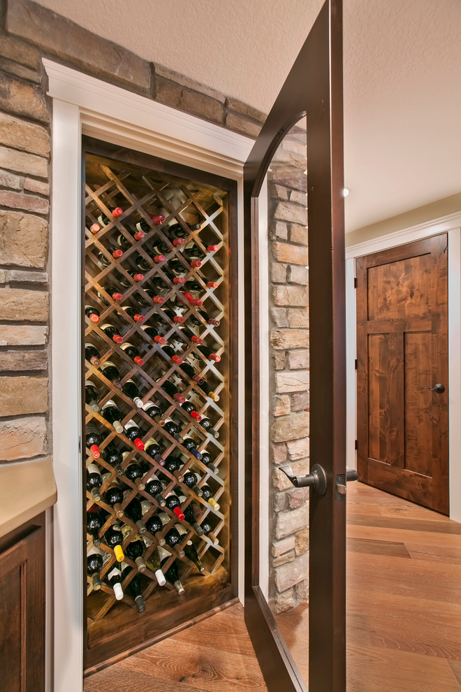 Idée de décoration pour une petite cave à vin chalet avec un sol en bois brun et des casiers losange.
