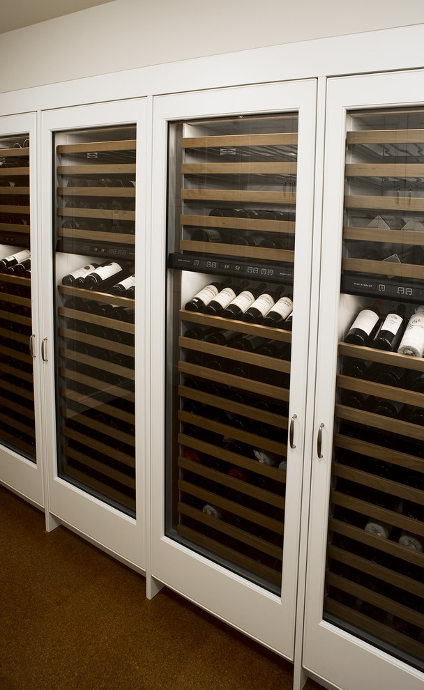 Bild på en stor funkis vinkällare, med korkgolv, vinhyllor och brunt golv
