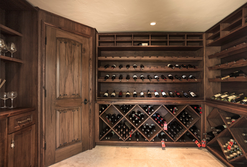 Inspiration for a large mediterranean wine cellar in Santa Barbara with travertine flooring and cube storage.