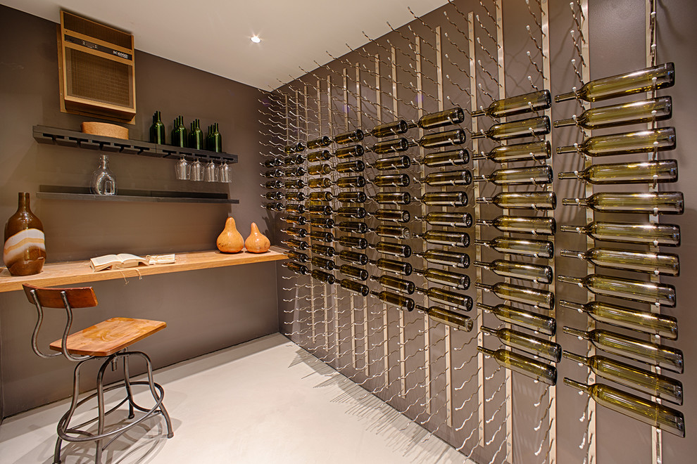 This is an example of a medium sized modern wine cellar in Houston with concrete flooring, display racks and grey floors.