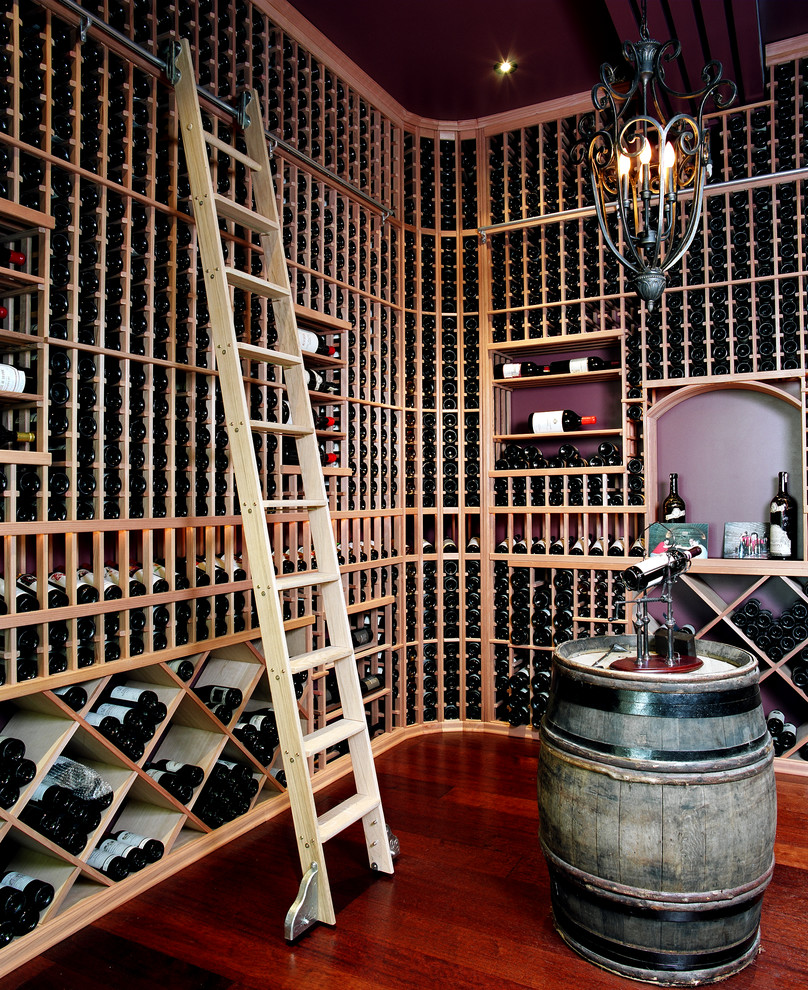 Idée de décoration pour une grande cave à vin tradition avec un sol en bois brun et des casiers.