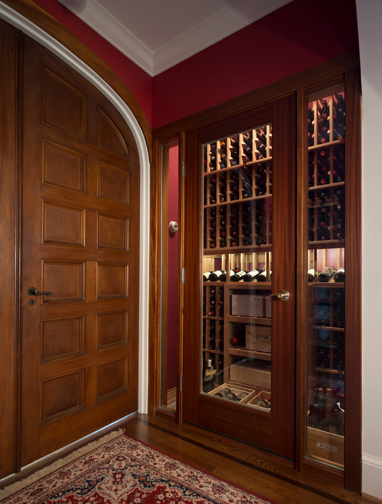 Cette photo montre une cave à vin chic de taille moyenne avec un sol en bois brun et des casiers.