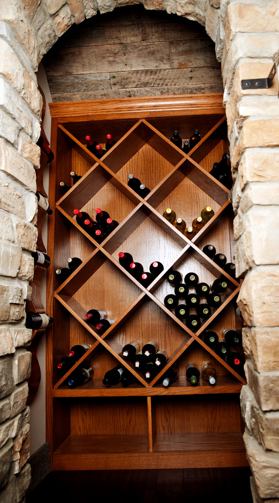 Foto på en liten medelhavsstil vinkällare, med mörkt trägolv och vinställ med diagonal vinförvaring