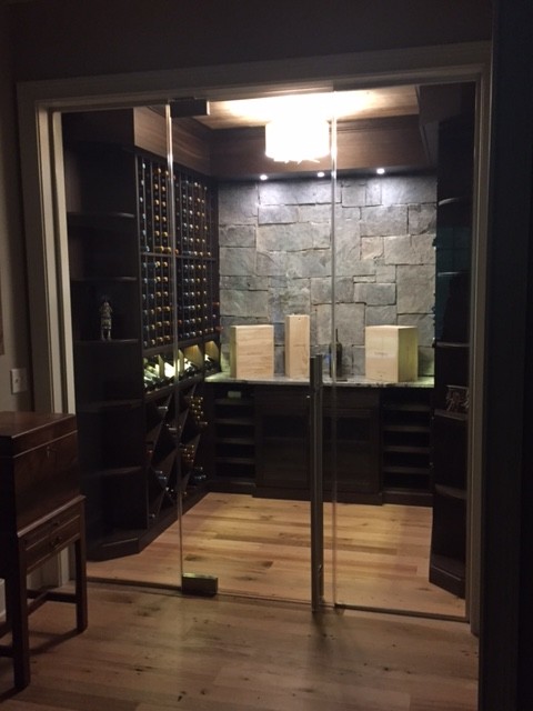 Aménagement d'une cave à vin classique de taille moyenne avec parquet clair, des casiers et un sol marron.