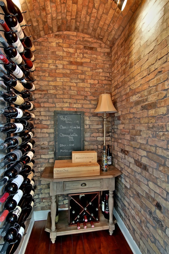 Exempel på en klassisk vinkällare, med mörkt trägolv, vindisplay och rött golv