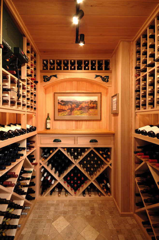 Aménagement d'une cave à vin classique de taille moyenne avec un sol en travertin, des casiers et un sol beige.