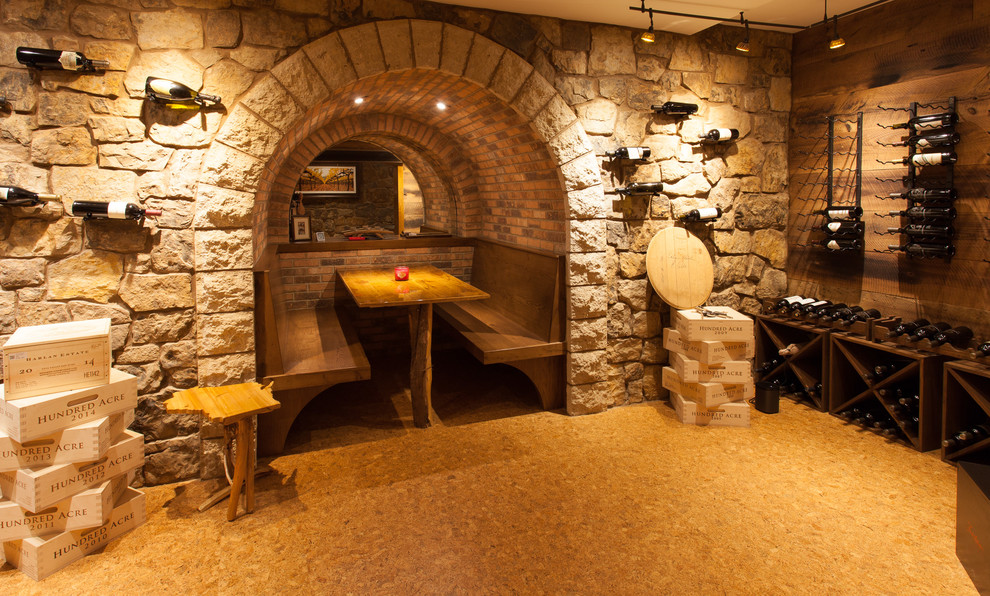 Exemple d'une grande cave à vin montagne avec un sol en liège, des casiers et un sol marron.