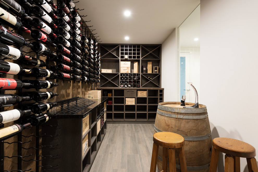 Aménagement d'une grande cave à vin contemporaine avec un sol en bois brun, un présentoir et un sol marron.