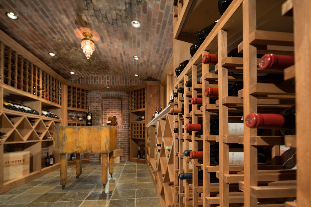 Idée de décoration pour une grande cave à vin tradition avec un sol en ardoise et des casiers.