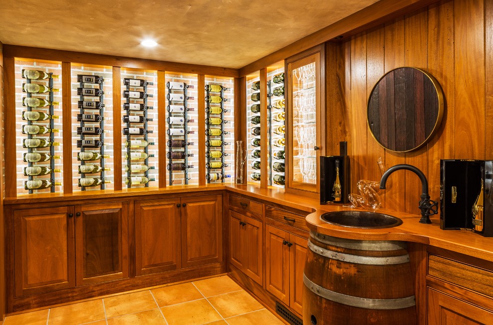 Cette photo montre une cave à vin chic de taille moyenne avec des casiers, tomettes au sol et un sol beige.
